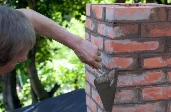 Pointing trowel refilling joints on a red brick chimney